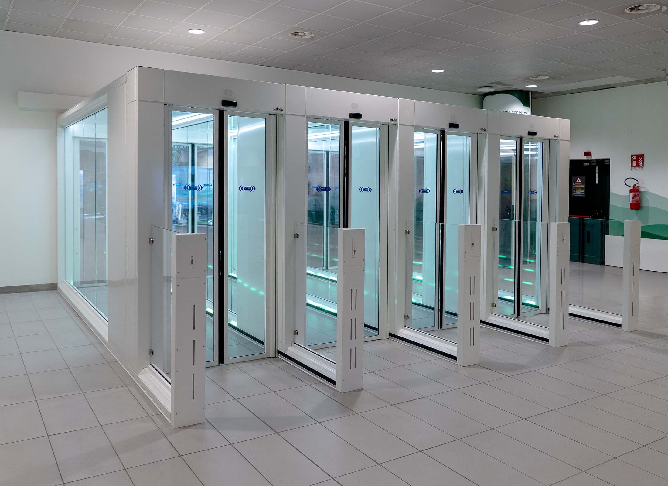 Vista laterale dei quattro One-Way Corridors FAAC con segnalazione LED verde integrata, installati nella Sala Arrivi Schengen dell'Aeroporto di Bologna
