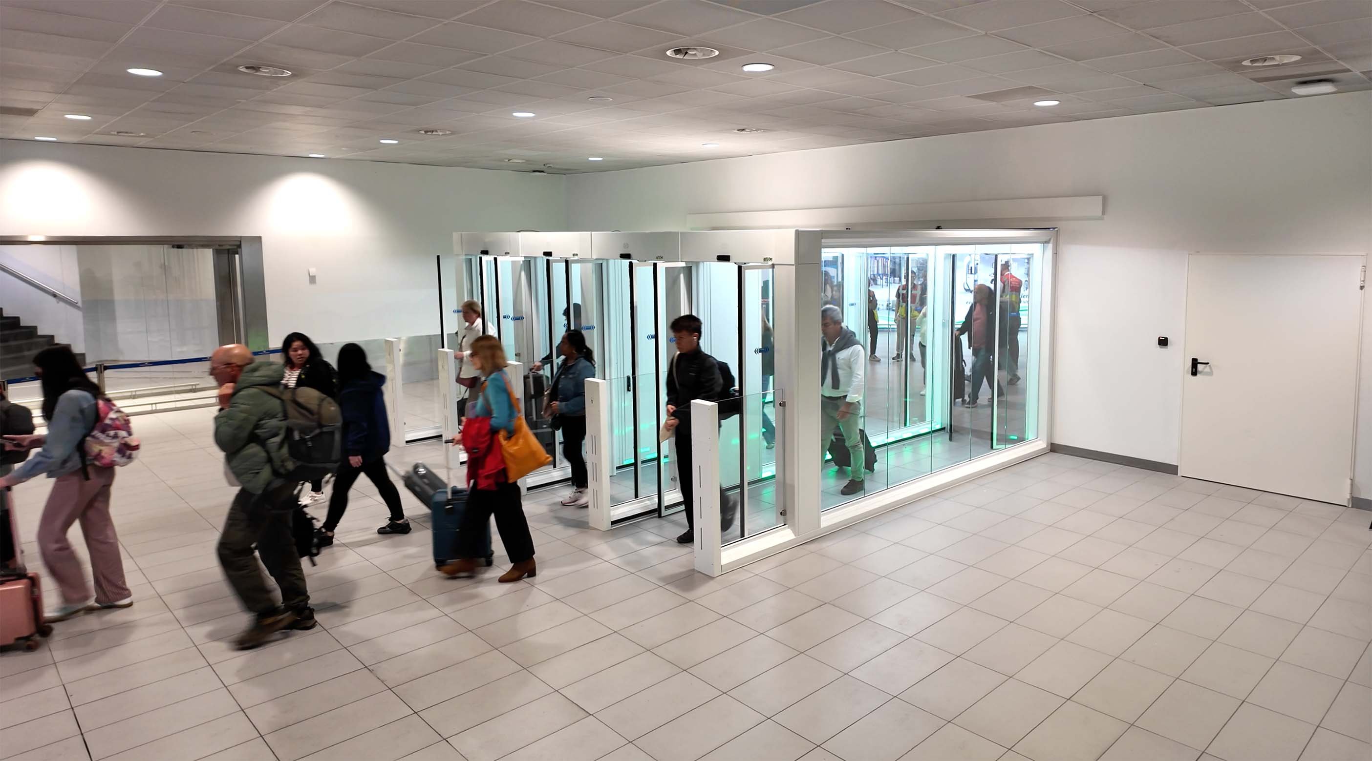 Passeggeri in transito attraverso i One-Way Corridors FAAC nella Sala Arrivi Schengen dell'Aeroporto di Bologna